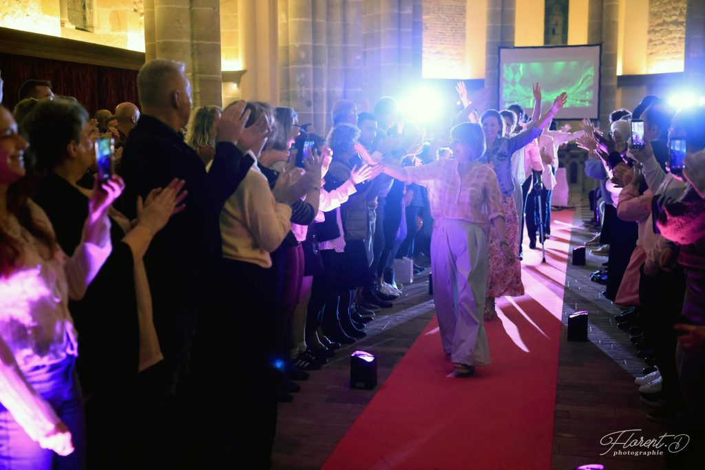 Défilé Tapis Rose à Moulins : une patiente salue le public sur le tapis rouge, entre deux haies d'honneur
